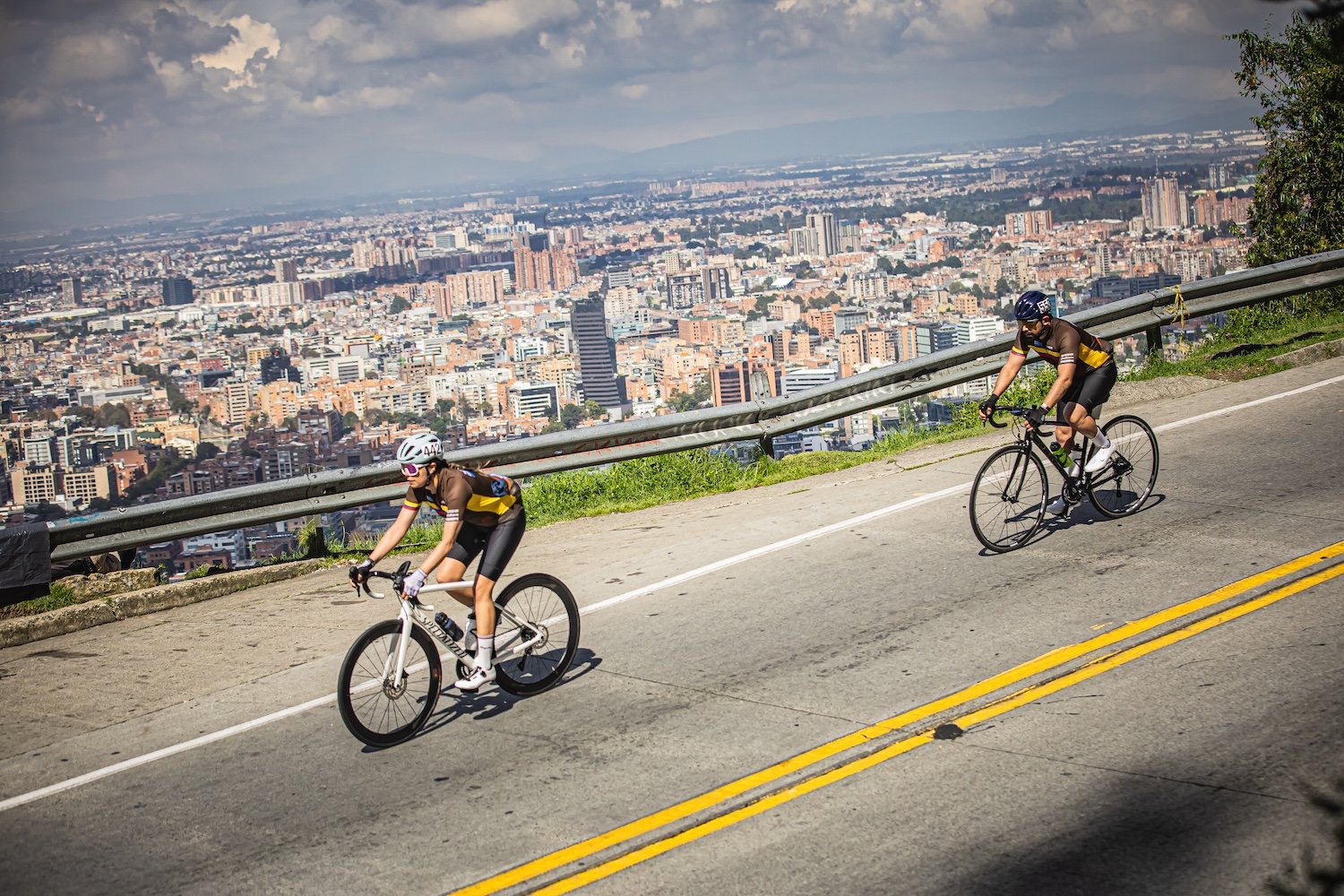 Cyclists climbing above Colombia during a Gran Fondo event with the city skyline below