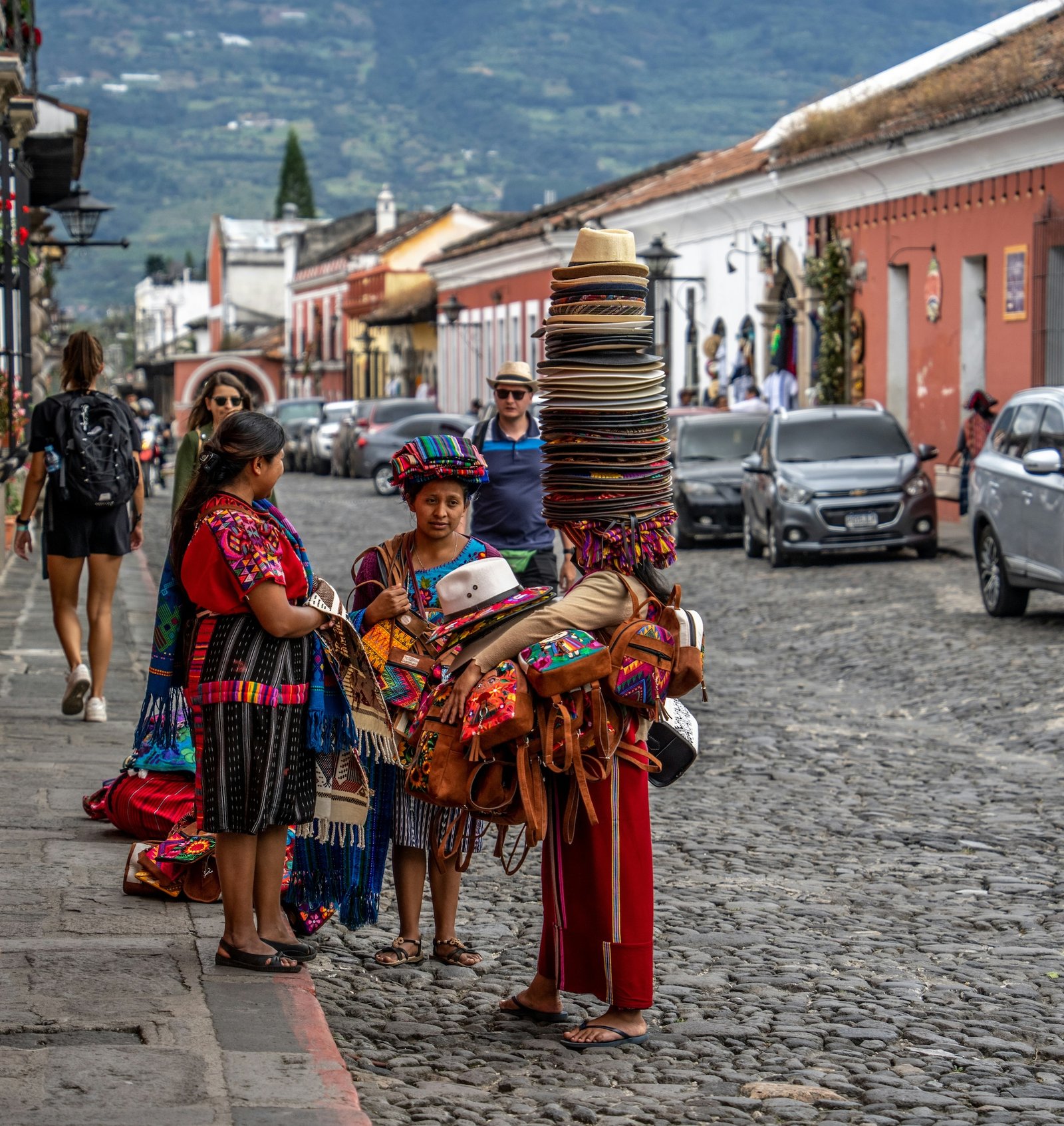 Indigenous women selling woven hats and handicrafts on a cobblestone street in Antigua, Guatemala
